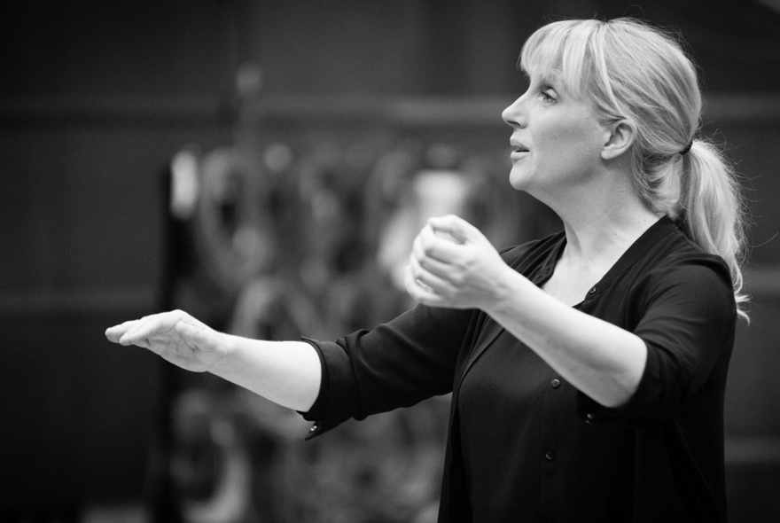A black and white image of conductor Sofi Jeannin performing. 