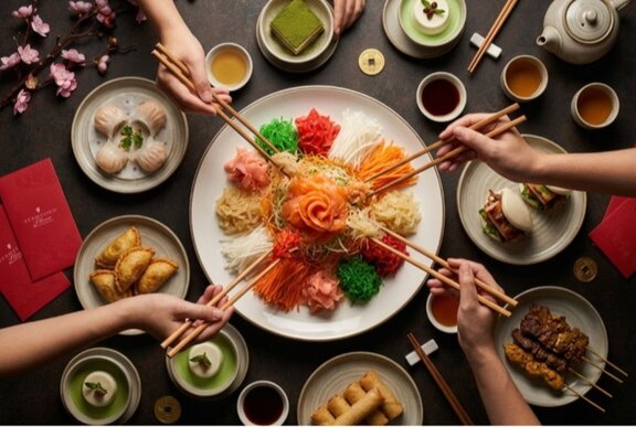 A communal dining scene where multiple hands use chopsticks to toss a colorful Yu Sheng salad.