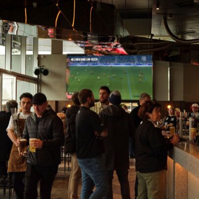 A busy bar with soccer on in the background.