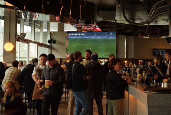 A busy bar with soccer on in the background.