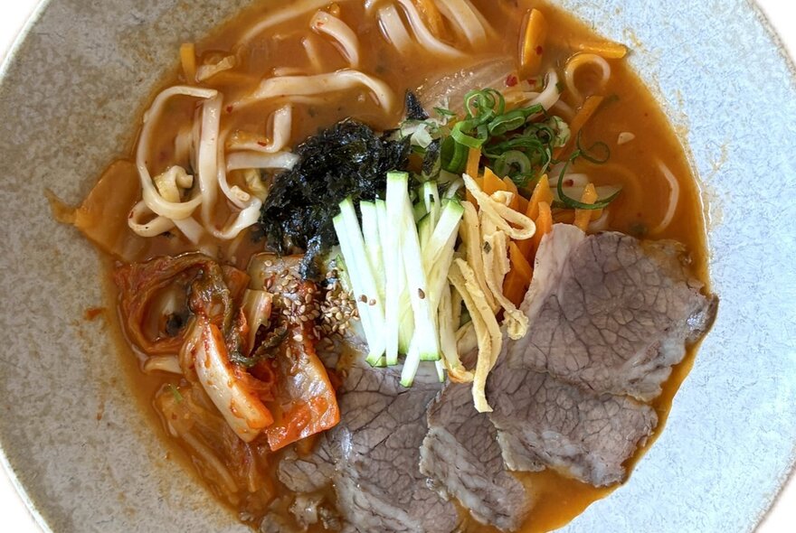 Korean soup bowl with noodles and thinly sliced beef in broth. 