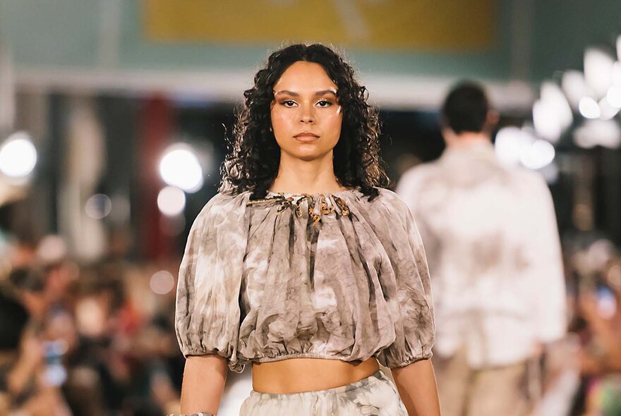 Runway model wearing flounced brown top.