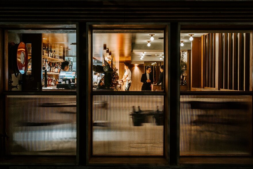 Looking through the windows at the interior of Circl Winehouse, with bar and wait staff inside.