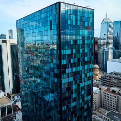 Glass skyscraper with blue windows in a city-centre locatio nsurrounded by midrise buildings.
