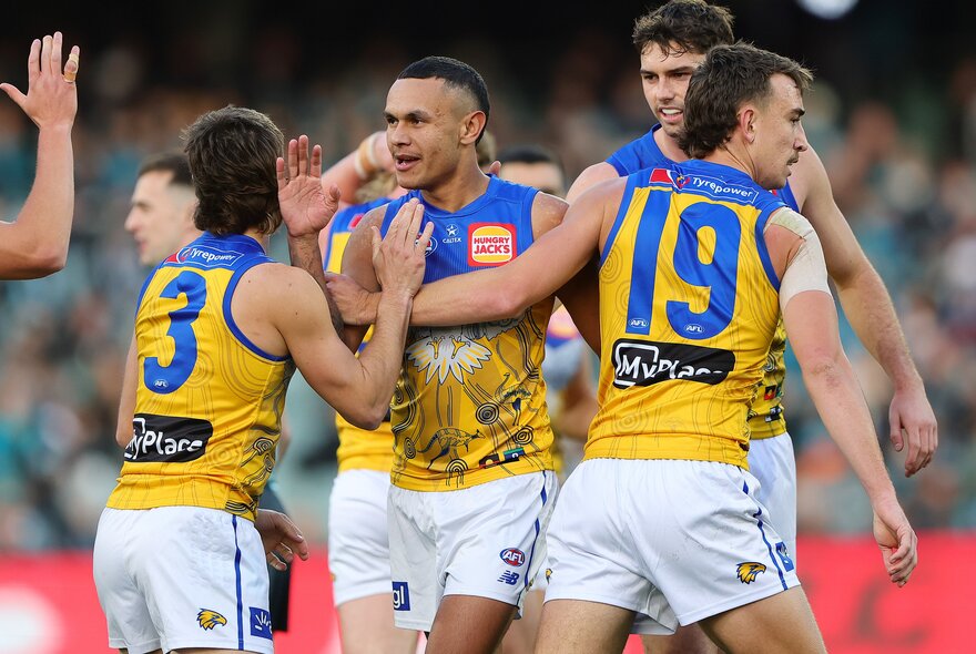 West Coast Eagles players come together in celebration during a match. 