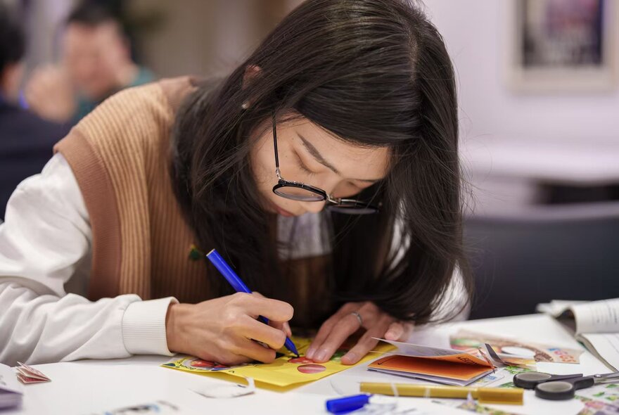Person working with pen and paper in a crafts workshop.