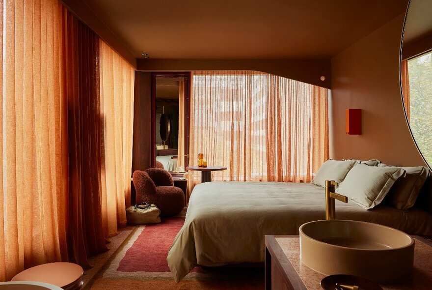 An orange toned hotel room with sheer orange drapes