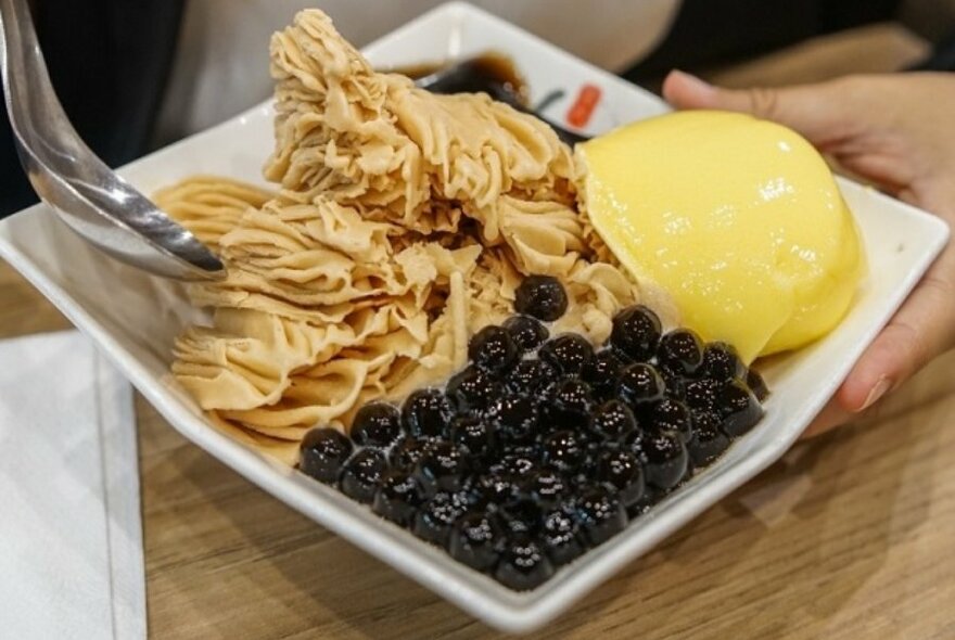 A white plate with shaved ice dessert in it