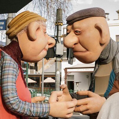 A pair of giant roving elderly character puppets on the streets of Carlton, performing as part of the Festival of Puppetry.