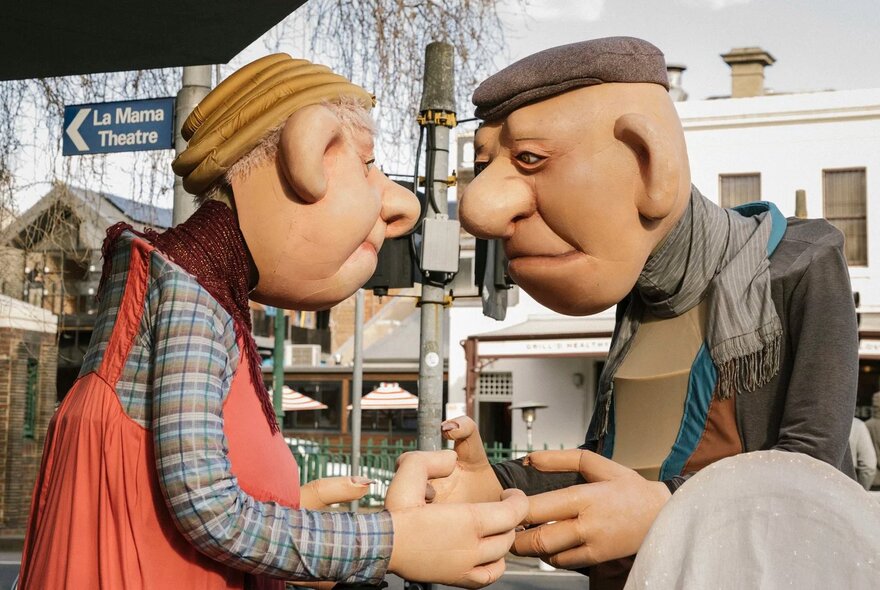 A pair of giant roving elderly character puppets on the streets of Carlton, performing as part of the Festival of Puppetry.