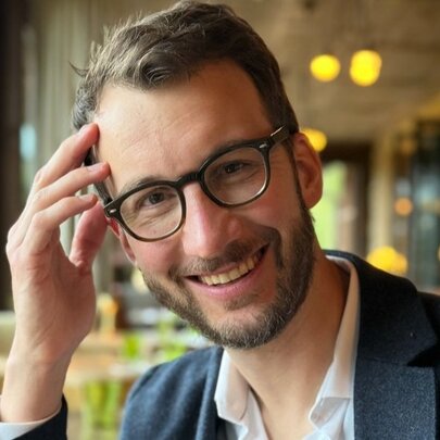 Author Stephen Fishbach, his head on his hand, with glasses and beard.