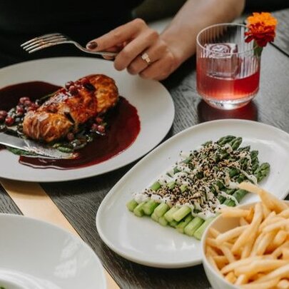 A person's hand holding a fork over a plate of food at a restaurant dining table.
