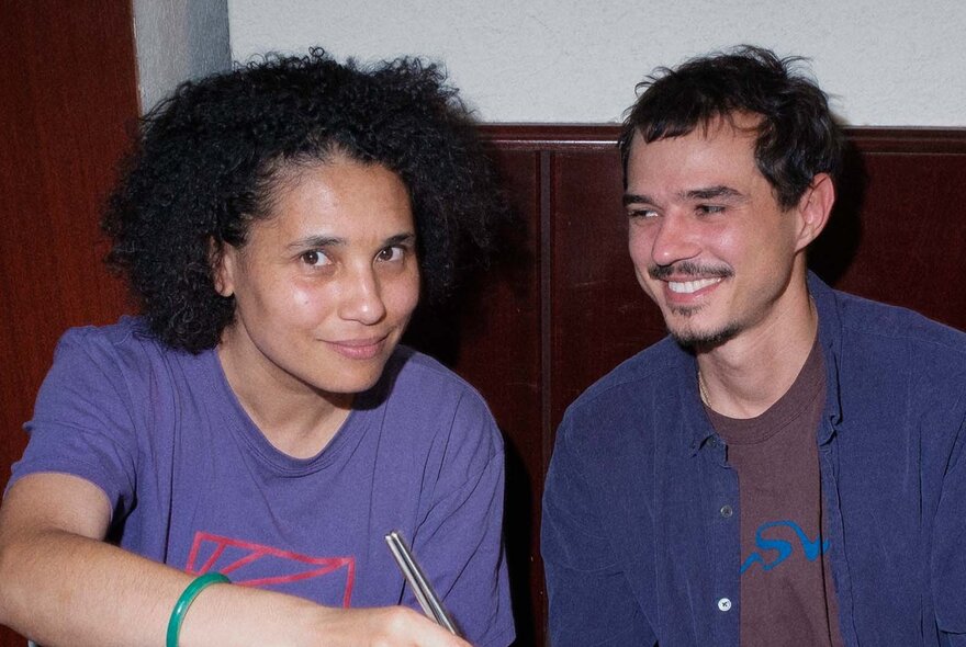 Two people seated next to each other, both slightly smiling.