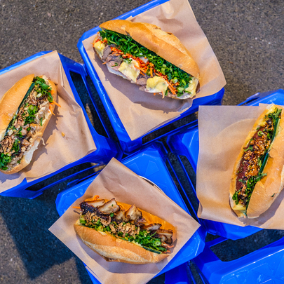 Four different flavoured banh mis on small blue stools.