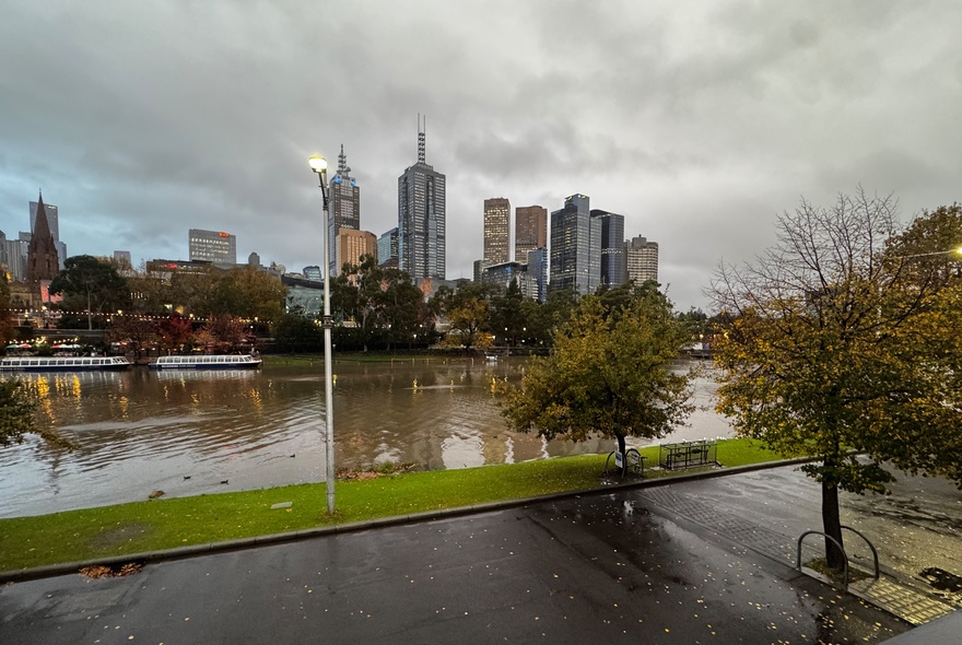 Wintry view of the Yarra River with city buildings and leafless trees against a grey sky.