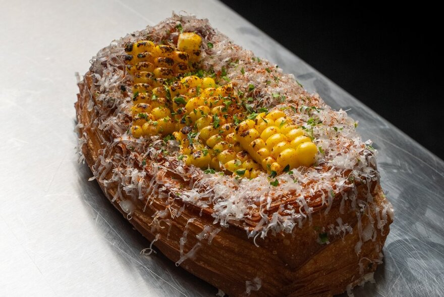 A pastry with corn and cheese on top.