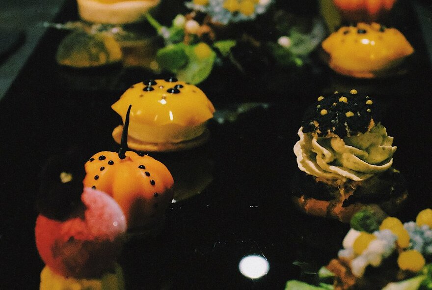 A display of individual desserts on a dark tray. 