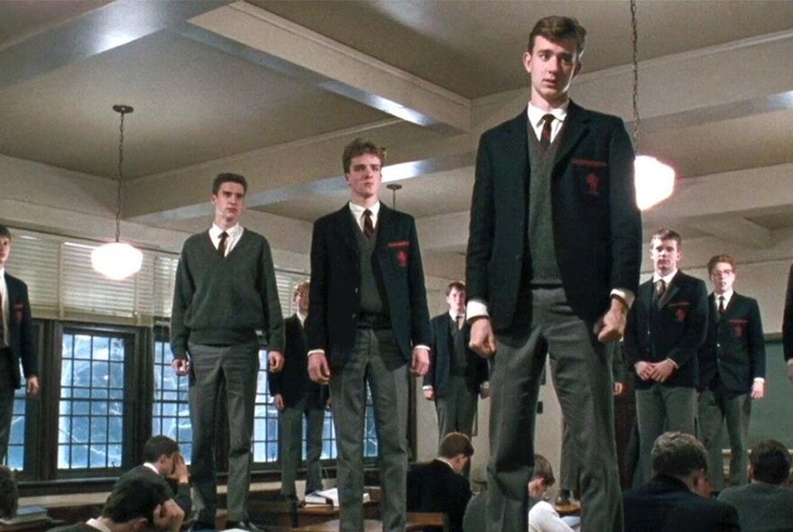 A still from an Australian movie, where teenage schoolboys in uniform are standing on their desks in a classroom.