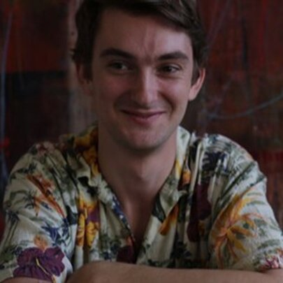 Man wearing patterned shirt, smiling with his arms folded.