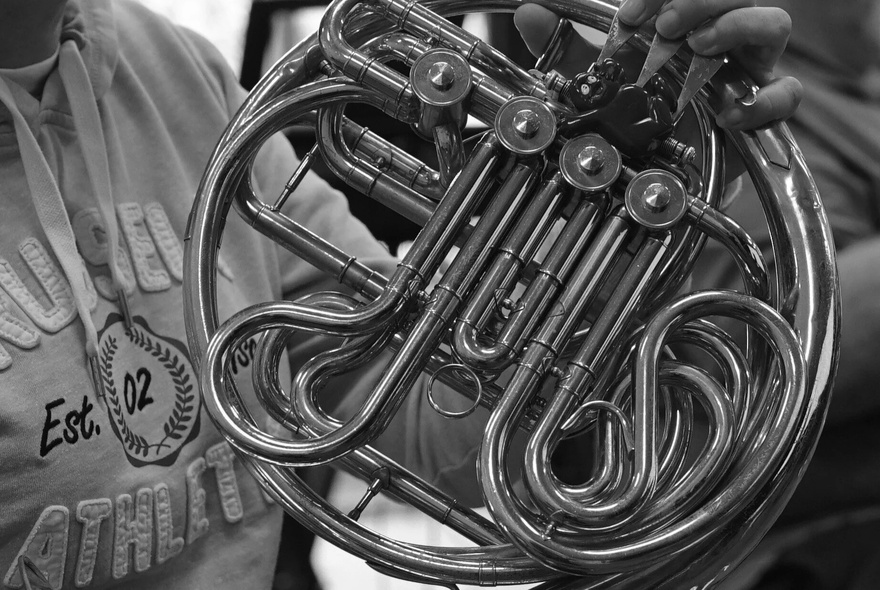 A black and white close up photo of a French Horn.