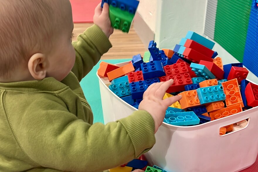 A small child playing with Duplo blocks.