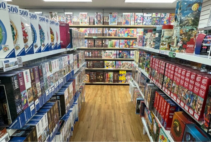 Hobbies store shelves packed with boxed games and products, along wall and aisles.