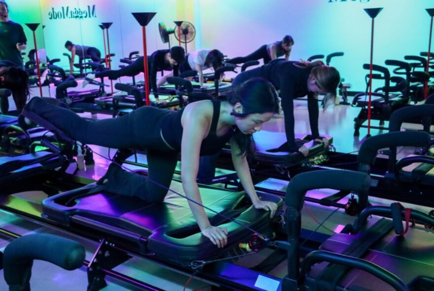 People exercising on a Megaformer machine in a studio space.
