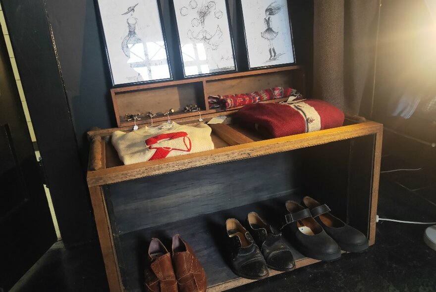 A display shelf of folded vintage clothing and vintage footwear.