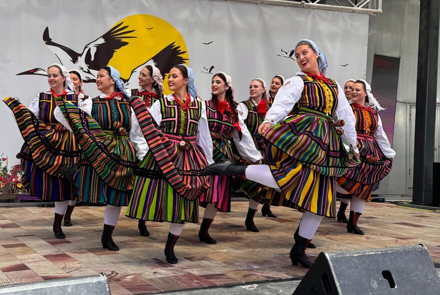 Dancers in traditional red, white and black attire, dancing on stage at the Polish Festival at Fed Square.