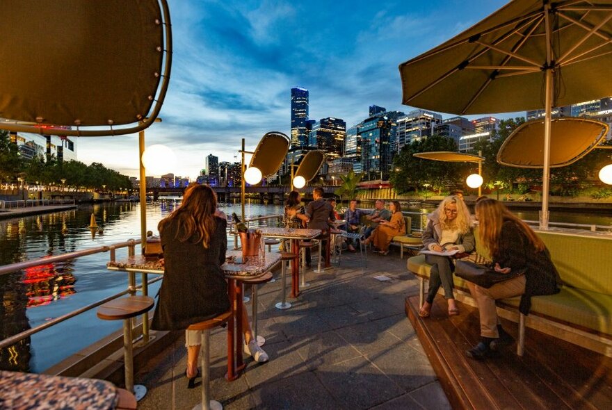 Sunset view from Ponyfish Island Bar women at tables looking happy and drinking.