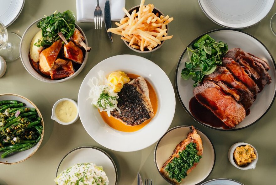 An array of tasty gourmet dishes laid out on a neutral surface, seen from above.