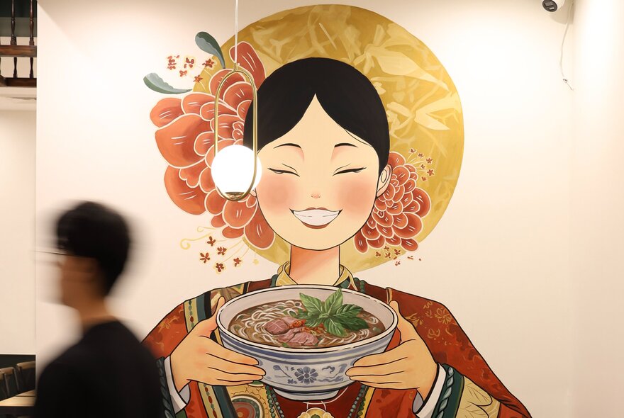A mural on the wall of a Vietnamese restaurant depicting a traditionally-dressed Vietnamese woman holding a bowl of pho.