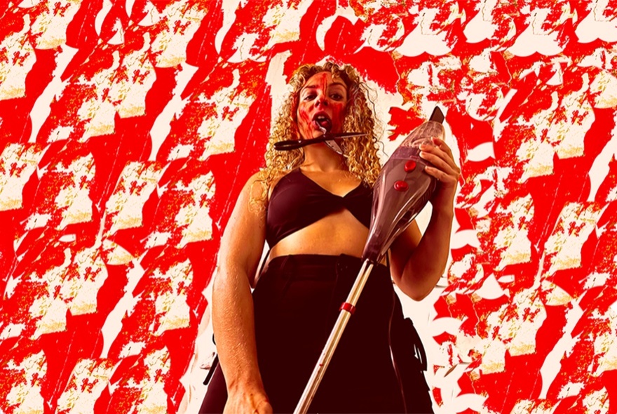 A female performer seen from below holding a vacuum cleaner; a mottled red and white background.