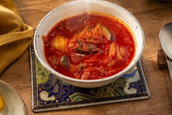 Bowl of spicy red chill soup on a table.