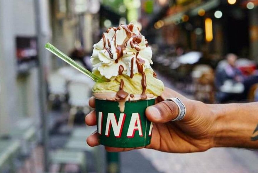 An ice cream in a cup, drizzled in chocolate.