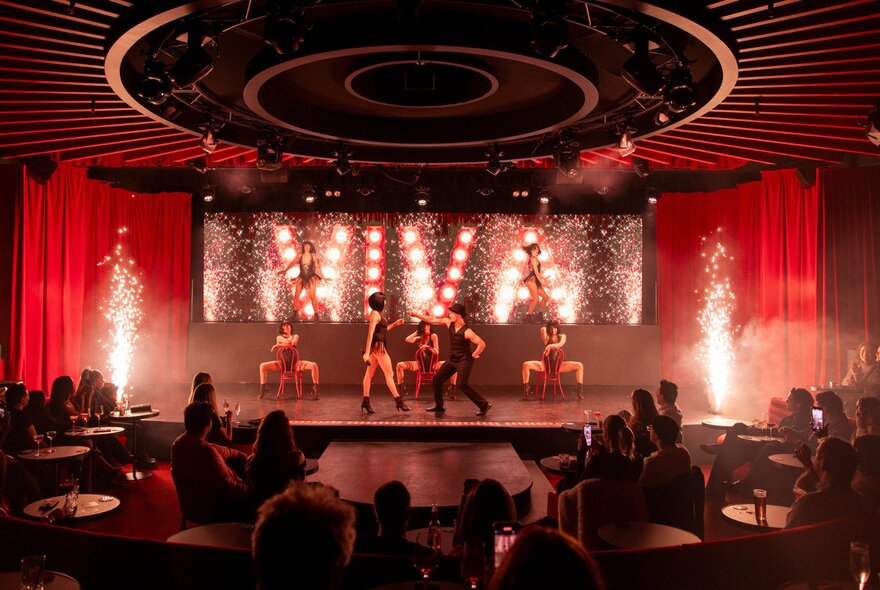Performers on stage at Viva club, dancing in front of a seated audience.