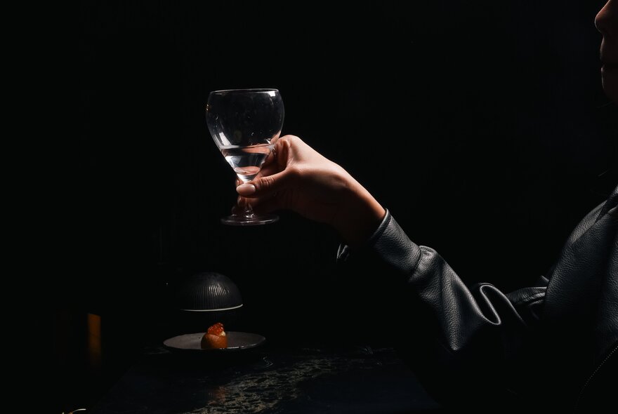 Hand holding a drink in a dark room.