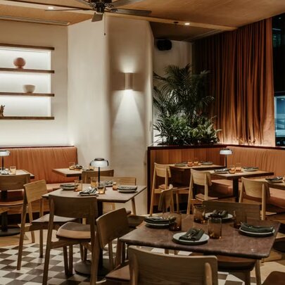 The interior of Barra restaurant, with orange bench seating and wooden tables and chairs.
