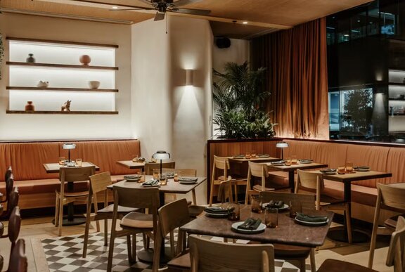 The interior of Barra restaurant, with orange bench seating and wooden tables and chairs.