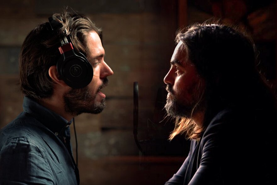 Two men facing each other in profile, one of them wearing headphones and singing.