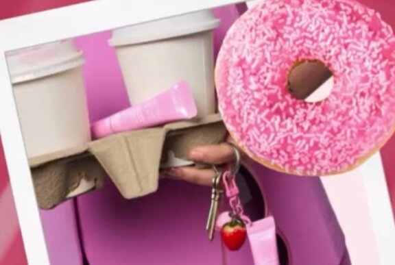 Pink freckled donut with coffee cups and cosmetics.