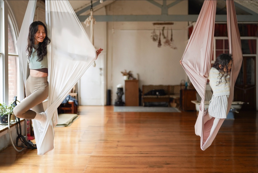 Children swinging on fabric suspension ropes in a studio setting.