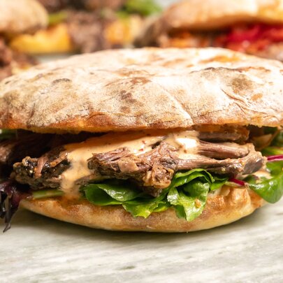 Bread bun with steak filling on a bench.