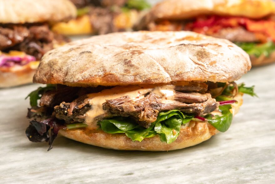 Bread bun with steak filling on a bench.