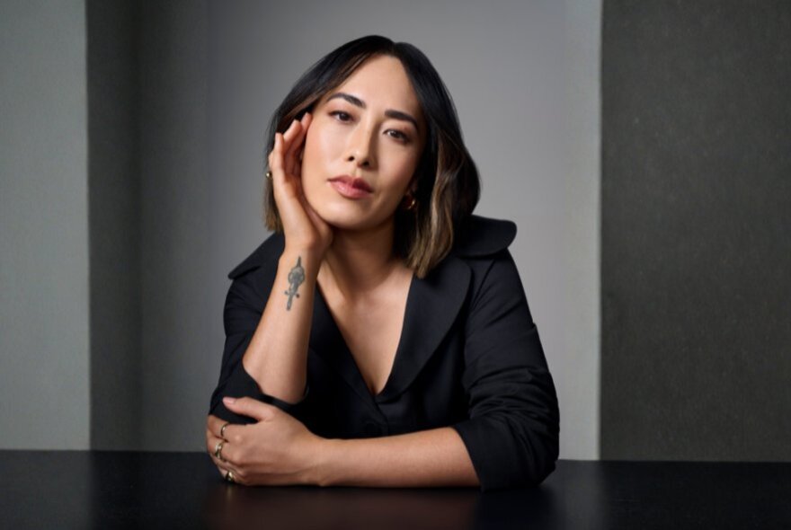 Food critic Melissa Leong, resting her hand on her face, wearing black.