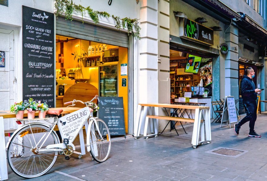 A tiny laneway cafe with a bicycle and plants outside.