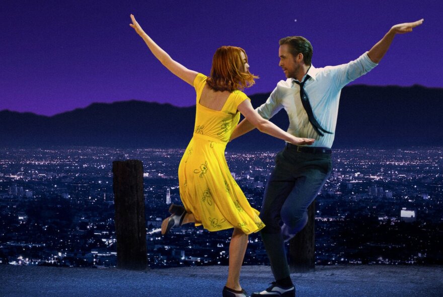 A still depicting a scene from the musical La La Land, featuring the male and female leads dancing at night against a backdrop of the twinkling valley of LA behind them.