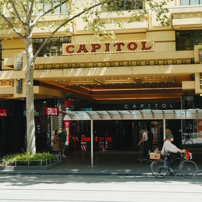 The exterior of The Capitol theatre, a cyclist riding past. 