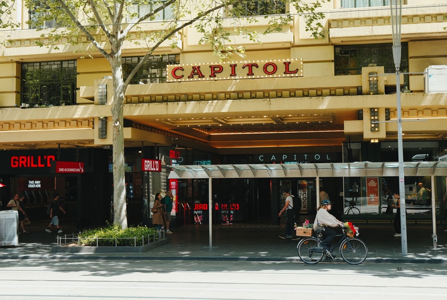 The exterior of The Capitol theatre, a cyclist riding past. 