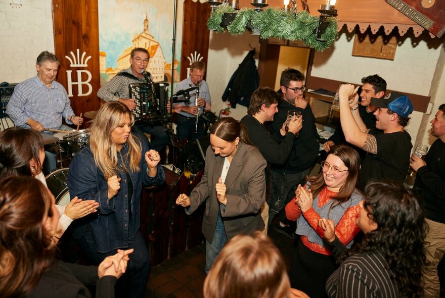 People dancing to a Bavarian band in a busy restaurant setting.